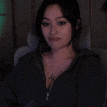 a woman wearing a black sweater and a necklace with a dolphin pendant