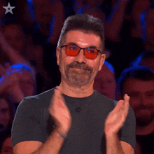 a man wearing sunglasses and a black shirt is clapping