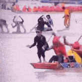 a man in a red shirt is riding a boat that says ' triathlon ' on it