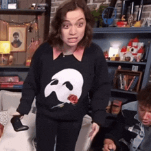 a woman wearing a black sweater with a skull and a rose on it
