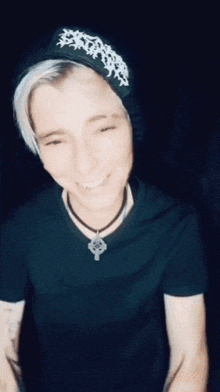 a person wearing a black shirt and a beanie with a cross on it
