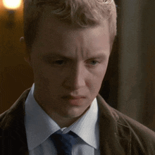 a young man in a suit and tie looks down
