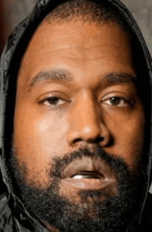 a close up of kanye west 's face with a beard and a hood on .