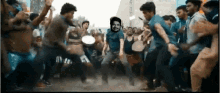 a man in a blue shirt is dancing in front of a crowd of people