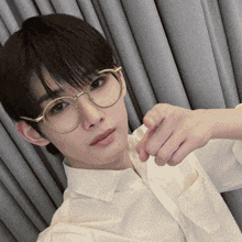 a young man wearing glasses and a white shirt is taking a selfie