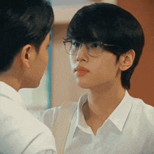 a man wearing glasses is looking at another man .