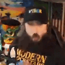 a man with a beard is wearing a black hat and a black shirt that says modern