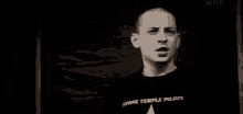 a black and white photo of a man wearing a black t-shirt with a white star on it .
