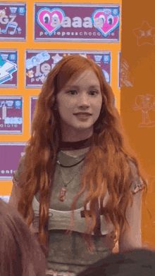 a girl with red hair is standing in front of a sign that says " aaa "