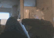 a blurry picture of a person sitting on a couch in a room