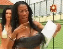 a woman in a black bra is holding a piece of paper in her hand .
