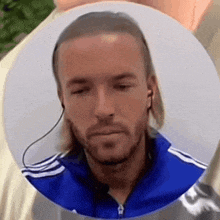 a man with long hair and a beard is wearing ear buds .