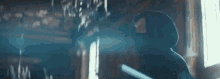 a man in a hooded sweatshirt is standing in a dark room holding a sword .