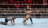 a woman is doing a handstand in a wrestling ring while a referee looks on .