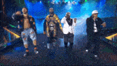 a group of men are standing on a stage and one of them has a championship belt around his neck