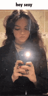 a woman is taking a selfie in front of a mirror with the words hey sexy above her
