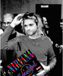 a black and white photo of kurt cobain with a colorful nirvana beautiful poster in front of him