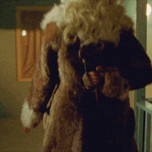 a woman in a fur coat is standing in a room