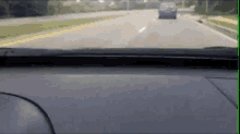 a car is driving down a highway with a blue van in the distance .