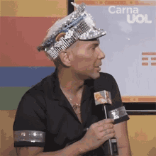 a man wearing a hat and holding a microphone is talking into it .