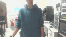 a man in a blue hoodie stands in front of a computer