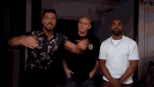 three men are standing next to each other and one of them is wearing a shirt that says hawaii