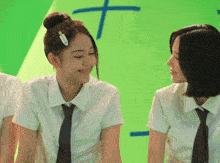 two girls in white shirts and ties are sitting in front of a green background with a cross on it