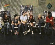 a group of people are sitting in chairs in front of a wall with a green clover on it