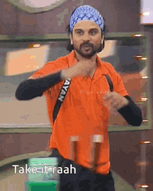 a man in an orange shirt is dancing with the words take it raah written below him
