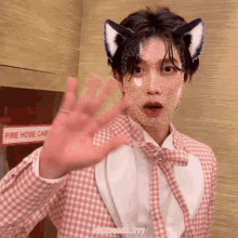 a man wearing cat ears is standing in front of a fire hose cabinet