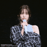 a girl in a plaid shirt is holding a microphone in her hand and is photographed by yaonge41