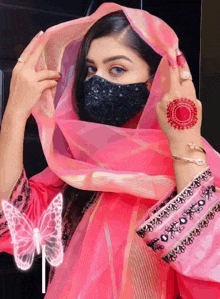 a woman wearing a pink dress and a black mask