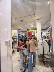 three girls are taking a picture in front of a mirror in a store that says vans