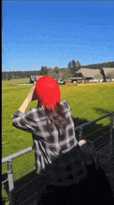 a woman in a red hat looks out over a field