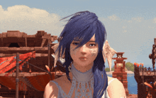 a woman with blue hair and feathers on her face looks at the camera