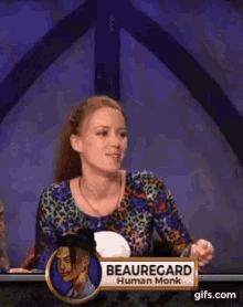 a woman is sitting at a table with a name tag that says beauregard human monk