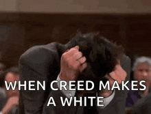 a man in a suit is covering his face with his hands and the words when creed makes a white