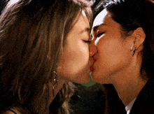 a close up of two women kissing with one wearing earrings with the letter z on them
