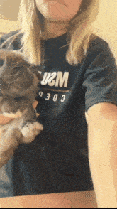 a woman holding a rabbit wearing a shirt that says u2m coed