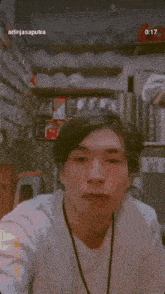a man in a white shirt is looking at the camera while another man stands in the background