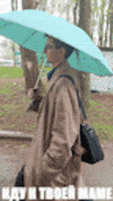 a man in a trench coat is holding a blue umbrella in the rain