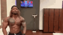 a shirtless man is standing in a locker room in front of a television and a scale .