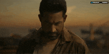 a man in a brown shirt is looking down with the words pranay varma behind him