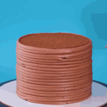 a person with red and white nails is cutting a chocolate cake with a knife