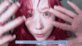 a close up of a woman 's face with red hair and purple nails .