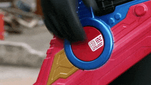 a person is pressing a red button on a red and blue toy gun