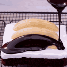 chocolate sauce is being poured on a cake with banana slices on top