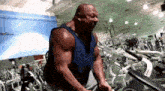 a man in a blue tank top is using a machine in a gym