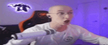 a bald man is sitting in a chair in front of a microphone in a room .