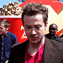 a man in a red shirt is standing in front of a mcdonald 's cup of popcorn